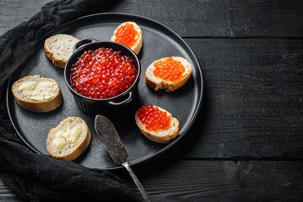 Sandwichs au caviar de poisson rouge, sur fond de table en bois noir avec espace de copie pour le texte