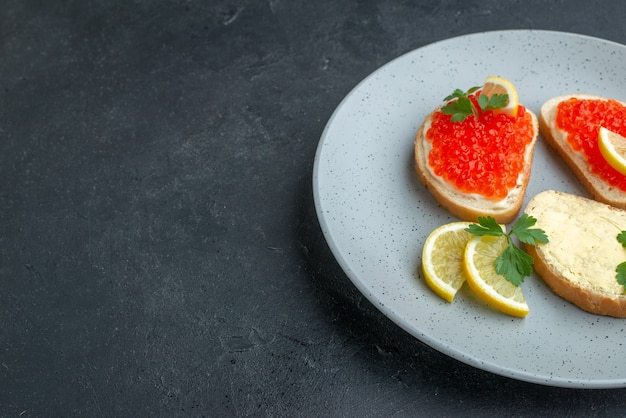 sandwichs au caviar vue de face avec du citron à l'intérieur de la plaque bleue sur une surface sombre