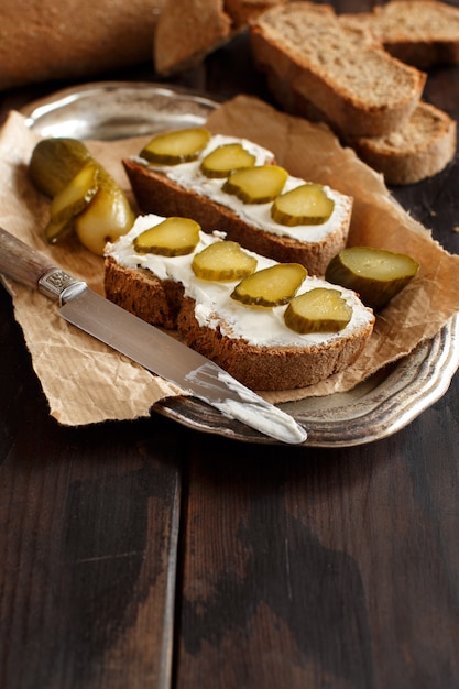 Sandwichs au fromage à la crème et concombre salé sur une table en bois