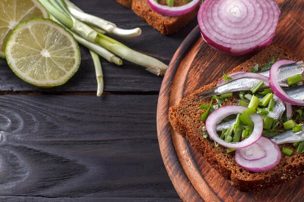 Sandwichs au pain noir avec carcasses de sprat salé aux oignons et persil