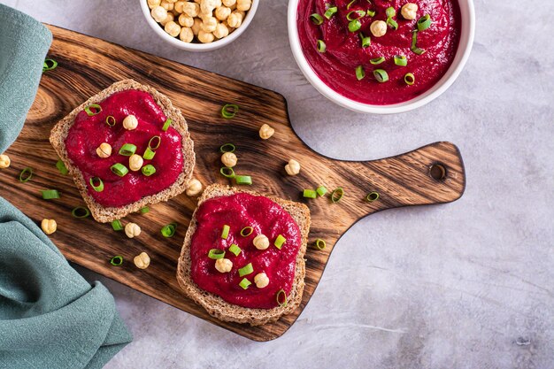 Sandwichs au pain de seigle faits maison avec houmous de betterave et herbes sur une vue de dessus de planche à découper