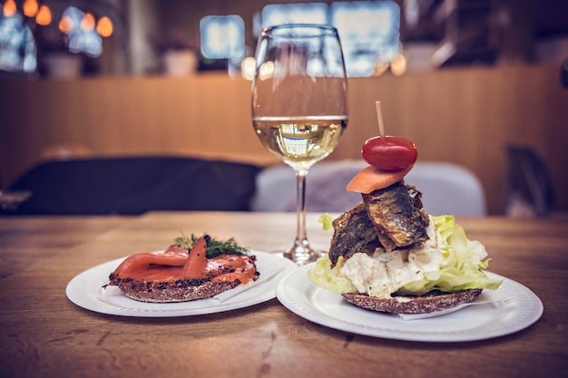 Photo des sandwichs au poisson et un verre de vin blanc sur la table au marché aux poissons d'helsinki, finlande