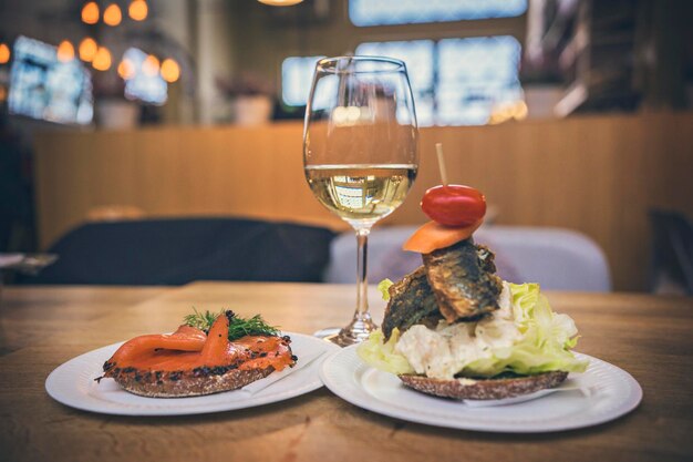 Des sandwichs au poisson et un verre de vin blanc sur la table au marché aux poissons d'Helsinki, Finlande