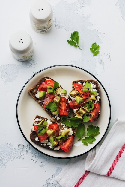 Sandwichs aux avocats, tomates cerises et fromage feta avec sauce balsamique et coriandre. Vue de dessus.