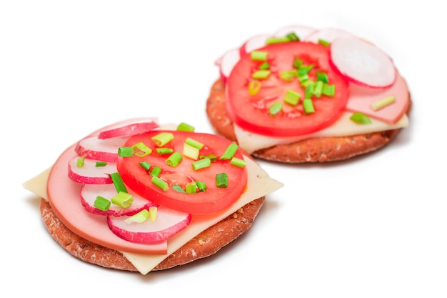 Sandwichs aux craquelins croustillants avec fromage à la saucisse de tomate, oignons verts et radis isolés