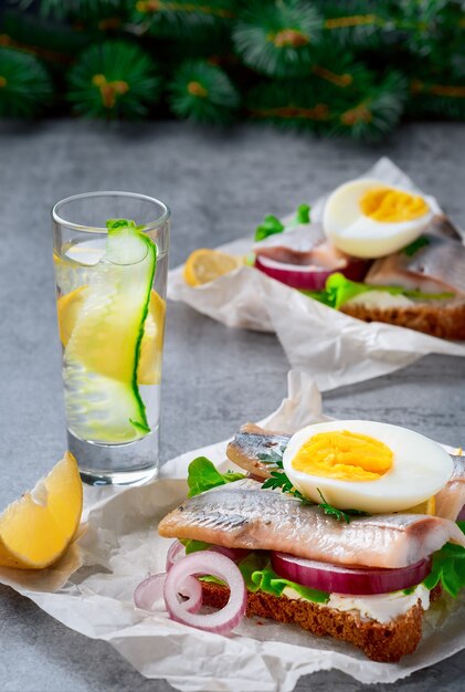 Sandwichs aux légumes et œufs de hareng, gros plan. Un verre de gin ou de vodka sur la table. Concept de collation, sandwich smorrebrod traditionnel