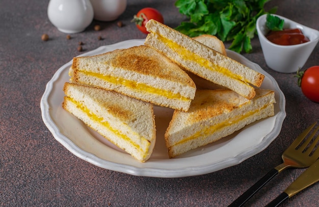 Sandwichs aux œufs et au fromage frits dans une poêle servis avec de la sauce tomate pour le petit-déjeuner sur une assiette blanche