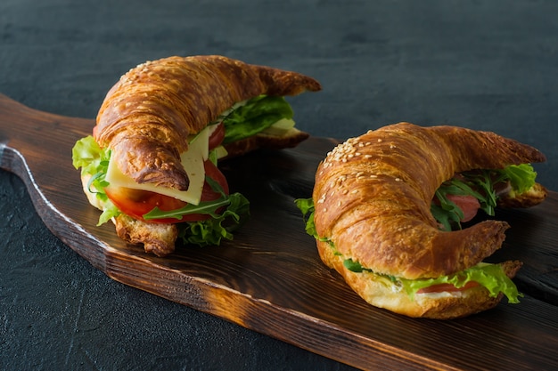 Sandwichs croissants au saumon salé sur un bureau, servis avec des feuilles de salade fraîche,