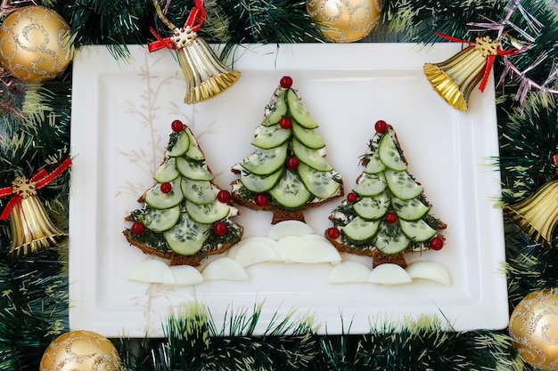 Sandwichs Du Nouvel An à Base De Pain Noir, De Fromage Et De Concombres Sous Forme D'arbre De Noël, Baies Décorées, Situés Sur Une Assiette Blanche, Vue De Dessus