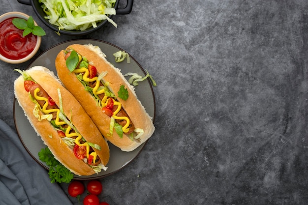 Sandwichs à hot-dog faits maison. Hot-dogs avec garniture de moutarde et de laitue sur un fond sombre. Espace de copie