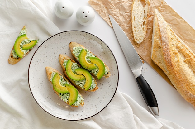 Sandwichs ouverts faits de baguette française fraîche, ricotta et épinards sur tableau blanc. Concept de petit déjeuner. Frais généraux, pose à plat