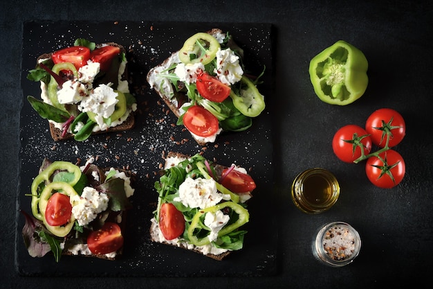 Sandwichs ouverts sains avec salade et fromage blanc sur fond noir.