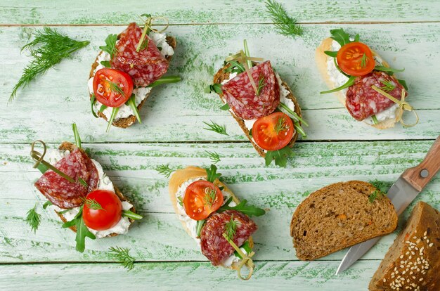 Sandwichs de pain grillé frais avec tomates cerises et salami au fromage cottage et roquette