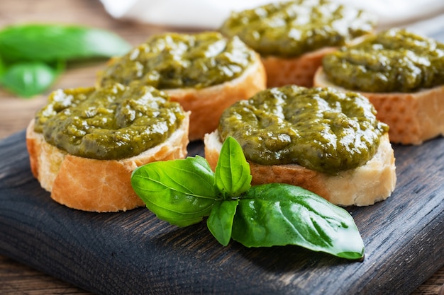 Sandwichs avec sauce pesto, feuilles de basilic frais et ail. Une délicieuse collation saine. Fond rustique en bois. fermer