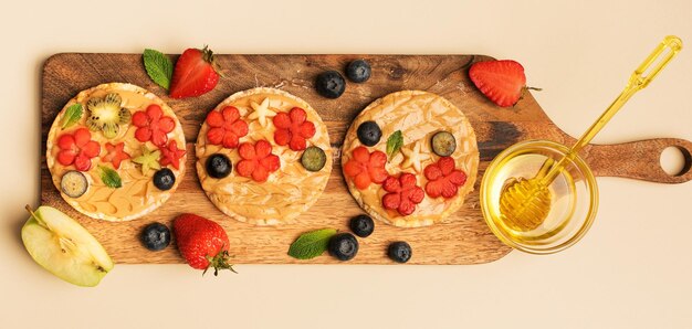 Sandwichs sucrés au beurre d'arachide avec des baies de fruits avec du miel sur une vue de dessus de planche de bois Bannière petit-déjeuner sain et savoureux