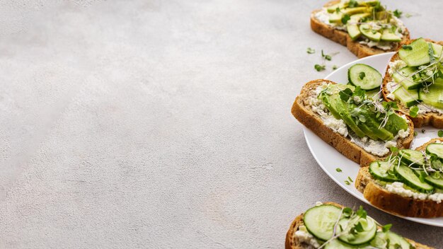 Sandwichs verts végétariens à l'avocat et au concombre avec des micro-verts sur fond clair