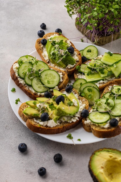 Sandwichs verts végétariens à l'avocat et au concombre avec des micro-verts sur fond clair