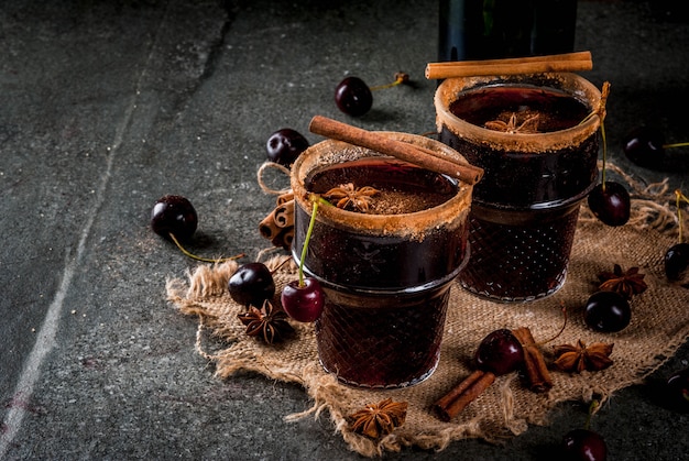 Sangria chaude cerise à la cannelle, anis, vin et épices Sur un fond de pierre sombre et en bois