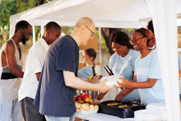 Des sans-abri de différents horizons reçoivent des repas réconfortants offerts par des bénévoles compatissants d'une banque alimentaire locale. Groupe caritatif communautaire soutenant et partageant de la nourriture gratuite aux pauvres et aux nécessiteux.