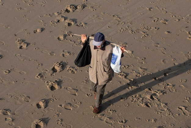 Sans-abri à la recherche de choses dans le sable sur la plage