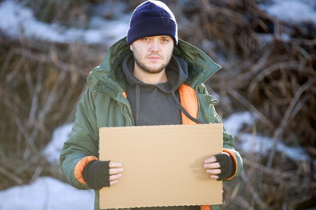 Photo un sans-abri tient un carton vierge pour votre texte