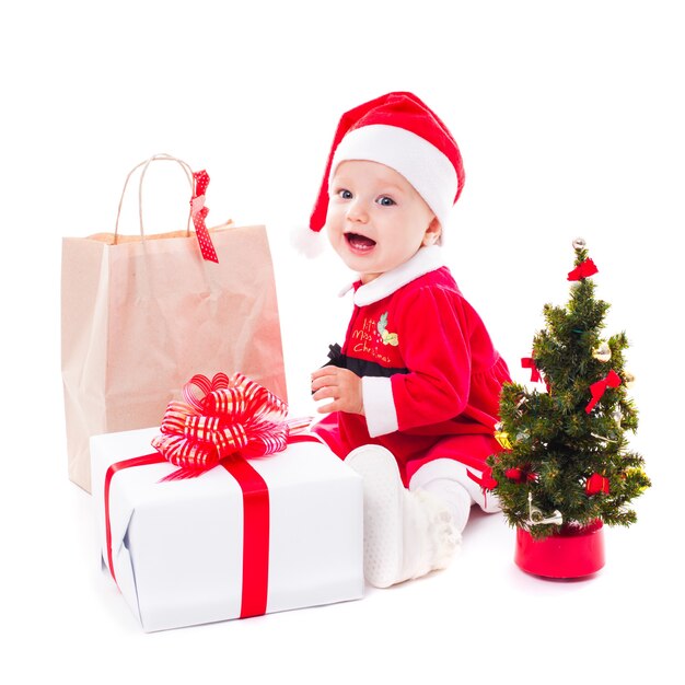 Santa baby girl avec boîte-cadeau et décorations de Noël sur blanc