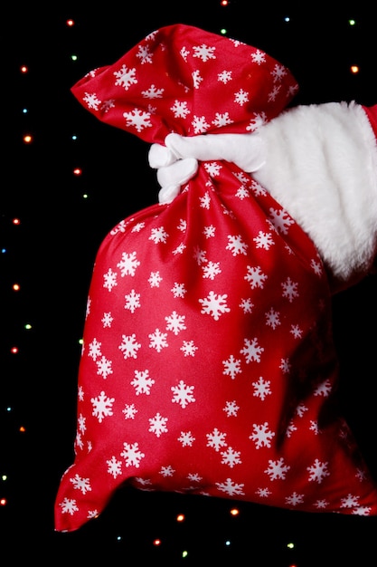 Santa Claus hand holding sac de cadeaux sur une surface lumineuse