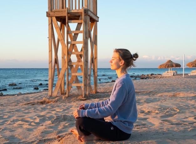 Santé et bien-être. Jeune femme en bonne santé pratiquant le yoga sur la plage au coucher du soleil