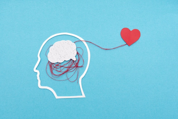 Santé émotionnelle et mentale avec un puzzle du cerveau connecté à un cœur sur fond bleu