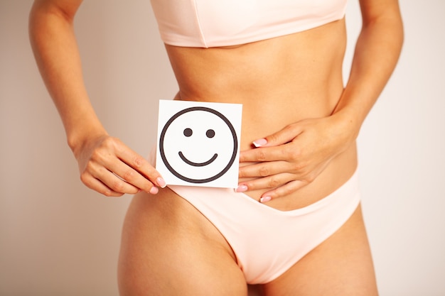 Santé des femmes, beau corps féminin en culotte avec carte de sourire.