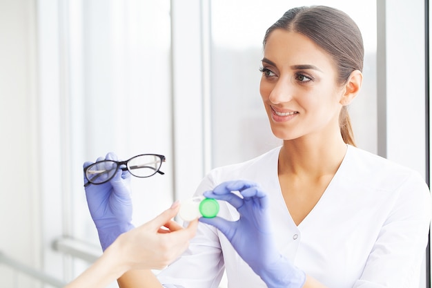 Photo santé. jeune fille détient des lentilles de contact dans les mains. portrait d'une belle femme aux yeux verts et aux lentilles de contact. apparence saine. haute résolution