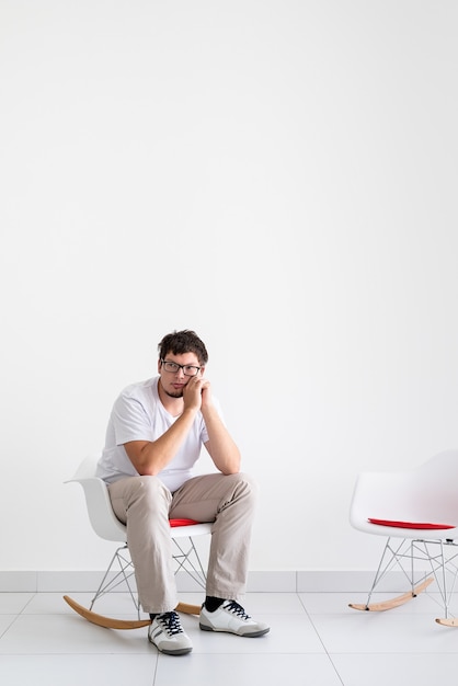 Photo santé mentale et soins de santé. jeune homme déprimé avec mal de tête assis sur la chaise