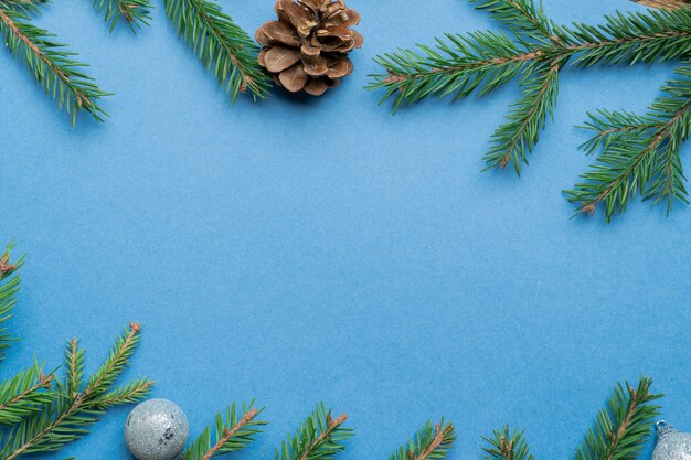 Sapin, branches d'épinette, pommes de pin et jouets d'arbre de Noël sur bleu avec copie espace