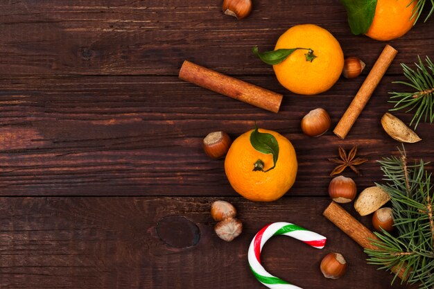 sapin, mandarines, canne en sucre, cannelle, amandes sur bois sombre, vue de dessus, espace copie