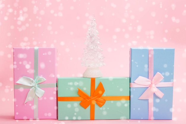 Sapin de Noël blanc en verre avec des cadeaux avec des arcs sur fond rose