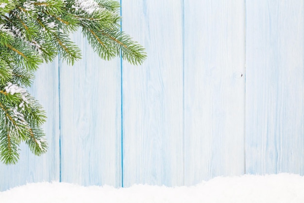 Sapin de Noël dans la neige devant un mur en bois