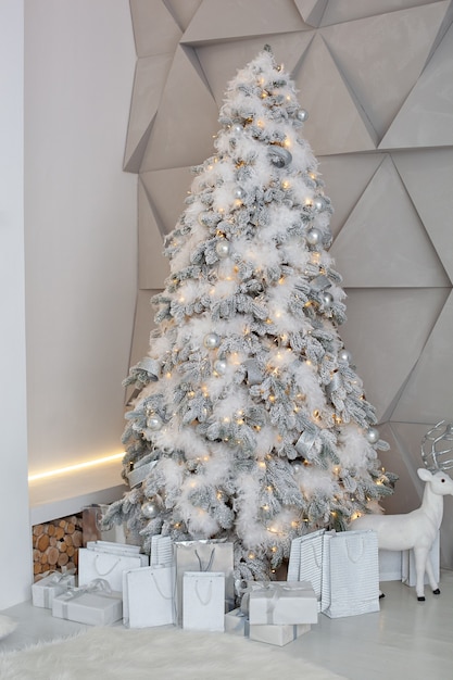 Sapin de Noël décoré de jouets, de balles et de guirlandes lumineuses dans la chambre