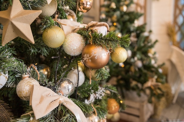 de sapin de Noël décoré de perles, d'argent, de cristal, de boules d'or et de jouets avec mur blanc.