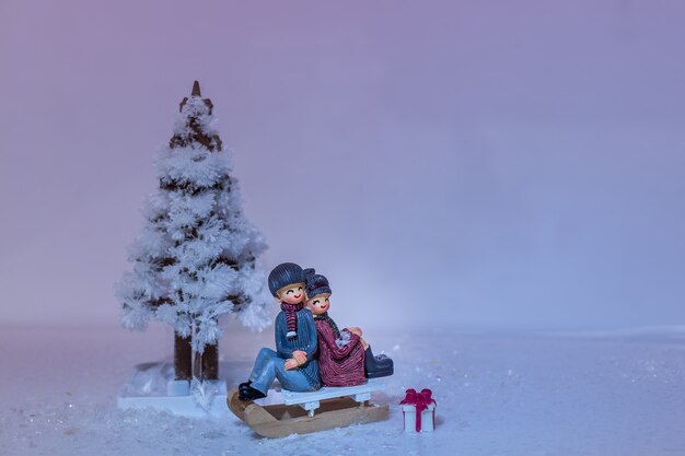 Sapin de Noël fait de cristaux, traîneau et doux couple sur la neige.