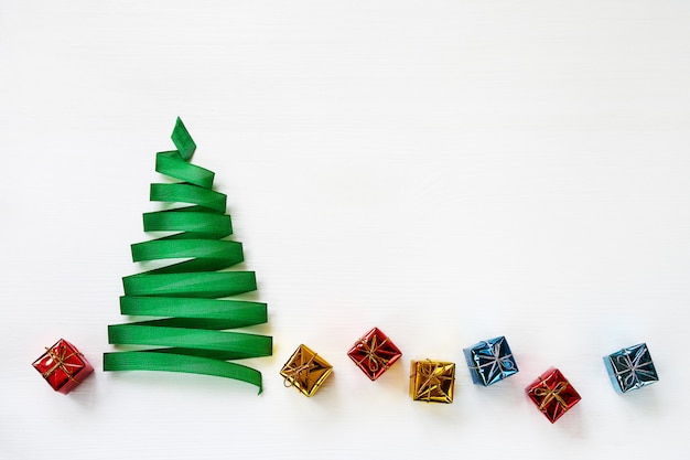 Sapin de Noël fait de ruban vert avec des petits cadeaux sur fond blanc. Espace de copie