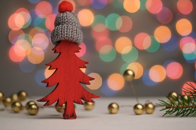 Sapin de Noël rouge dans un chapeau, des cadeaux, des boules et une décoration de nouvel an bokeh.