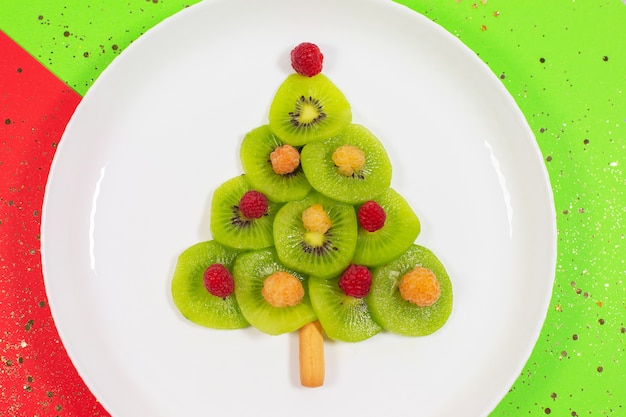 Sapin de Noël en tranches de kiwi table de couleurs d'hiver. Idée créative pour le petit déjeuner de Noël ou les desserts festifs du Nouvel An pour les enfants. Vue de dessus.