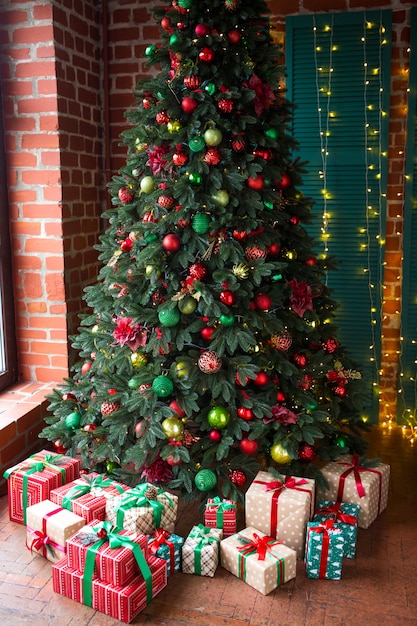 Sapin de Noël vert décoré de cadeaux de Noël et d'une guirlande.