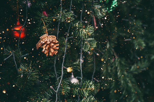 Sapin de Noël vintage avec décoration en forme de pomme de pin et lumière scintillante.