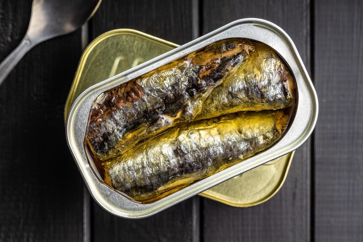Photo sardines en conserve poisson de mer en boîte de conserve sur table noire vue de dessus