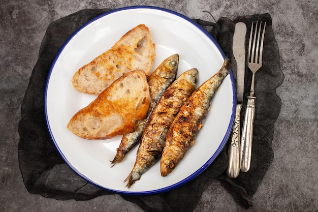 Sardines grillées avec sauce sur du pain frais sur un plat blanc