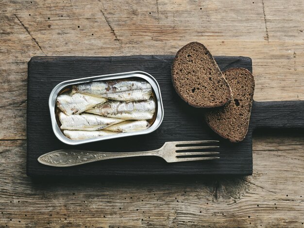 Les sardines ouvertes peuvent sur la vieille table de cuisine en bois, vue de dessus