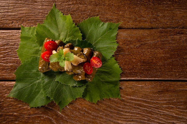 Photo sarma - riz et menthe enveloppés dans des feuilles de vigne sur fond de bois.