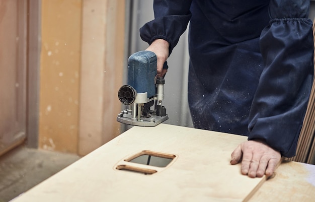 Sarpenter travaillant avec une fraiseuse Menuiserie menuiserie et fabrication de meubles Charpentier professionnel coupant du bois dans un concept industriel d'atelier de menuiserie