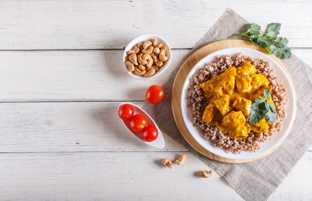 Sarrasin au poulet curry sauce à la noix de cajou sur fond en bois blanc